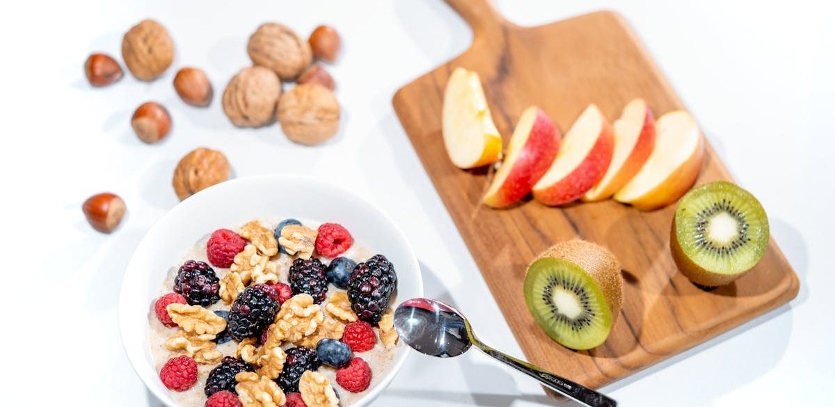 A nutritious breakfast bowl featuring fresh berries and walnuts, served with sliced fruit and kiwi.